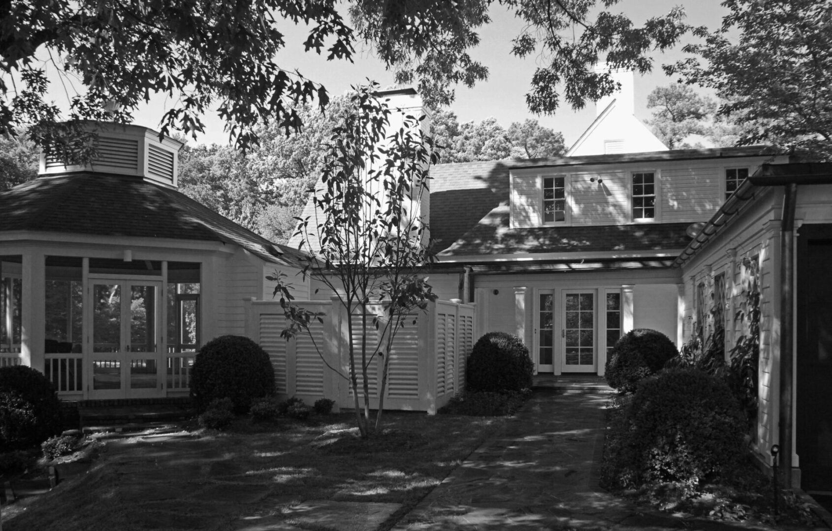 A black and white photo of two houses in the yard.