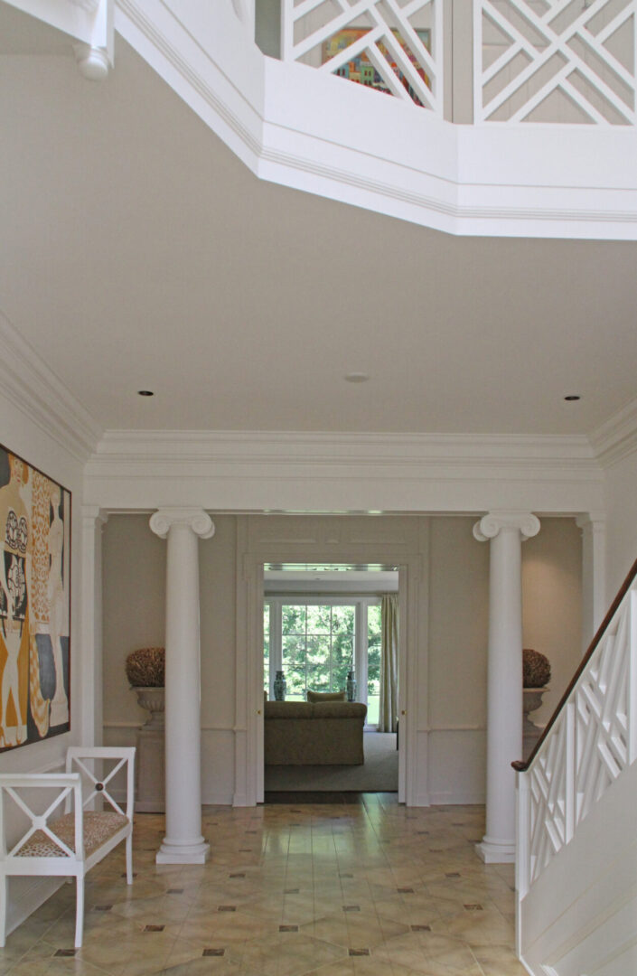 A hallway with columns and a painting on the wall.