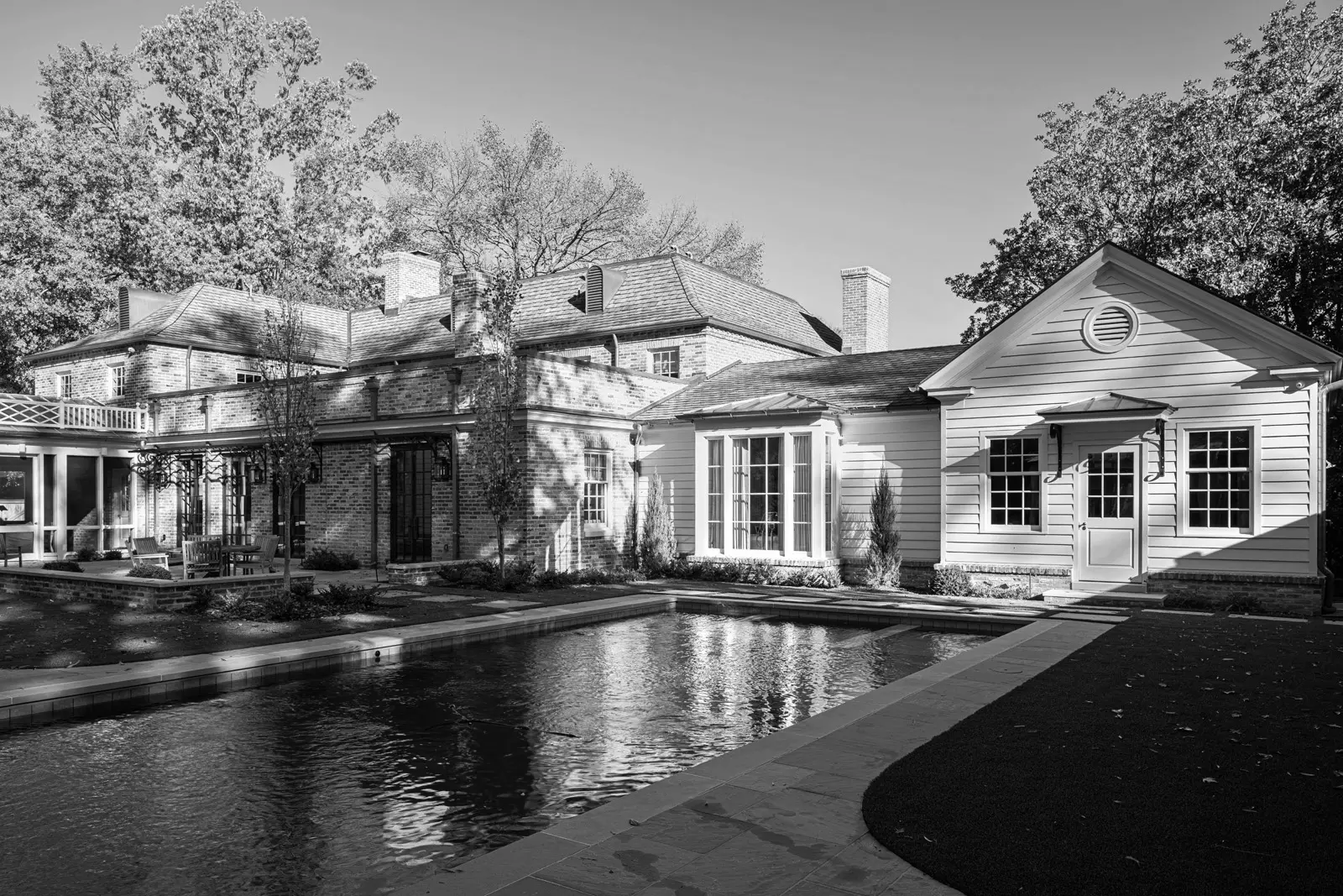 A black and white photo of a house with a pool.