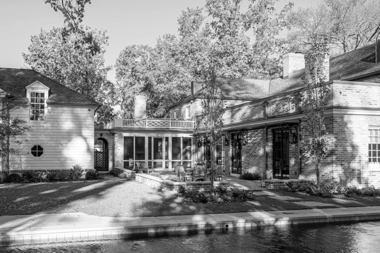 A black and white photo of a house with trees in the background.