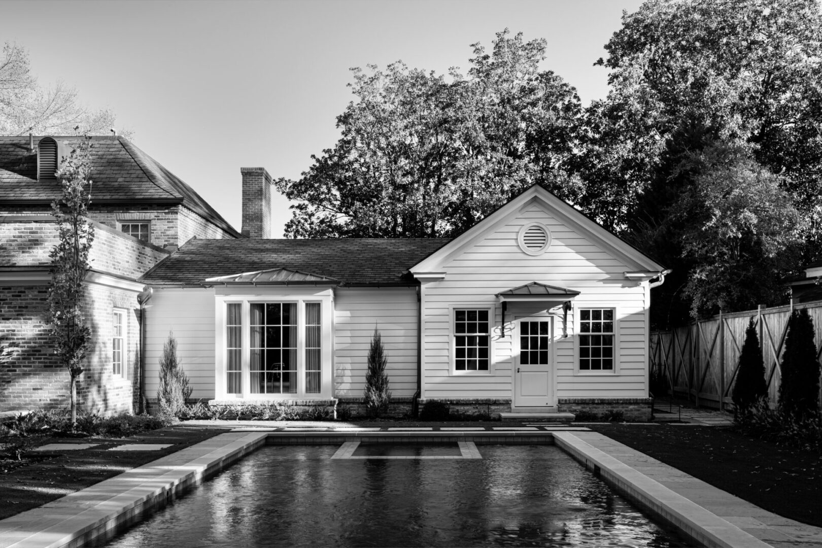 A black and white photo of a house with a pool.