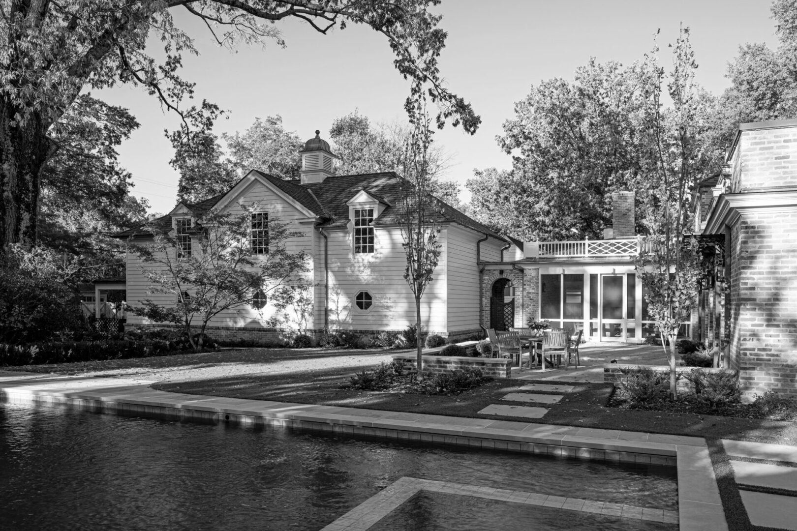 A black and white photo of a house with trees in the background.